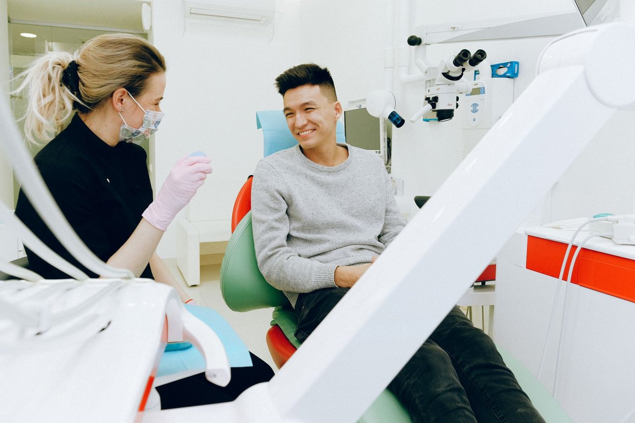 Behandlerin im Gespräch mit einem Patienten im Behandlungsstuhl